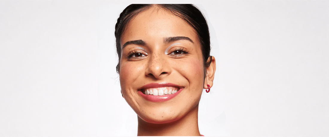 A woman smiling wearing the essence foundation stick behind a white background.  