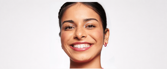 A woman smiling wearing the essence foundation stick behind a white background.  